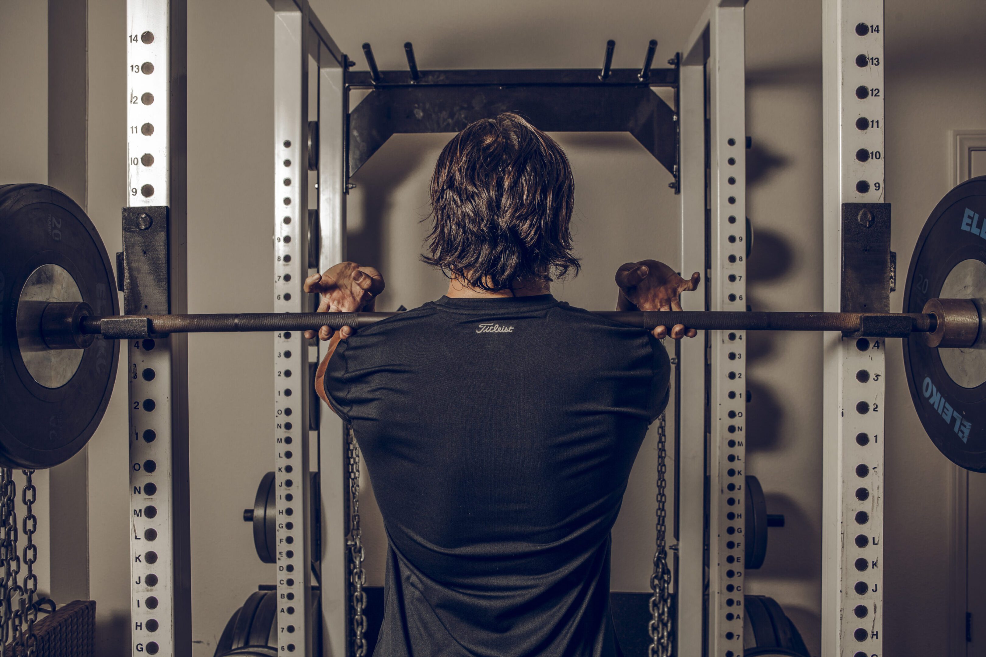 Person performing barbell squat in power rack