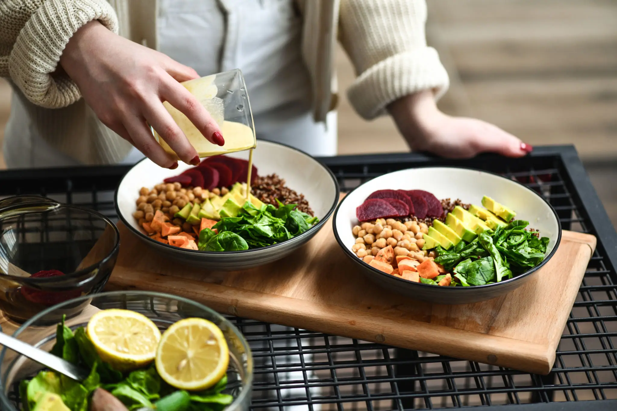 Pouring dressing over two vegan Buddha bowls