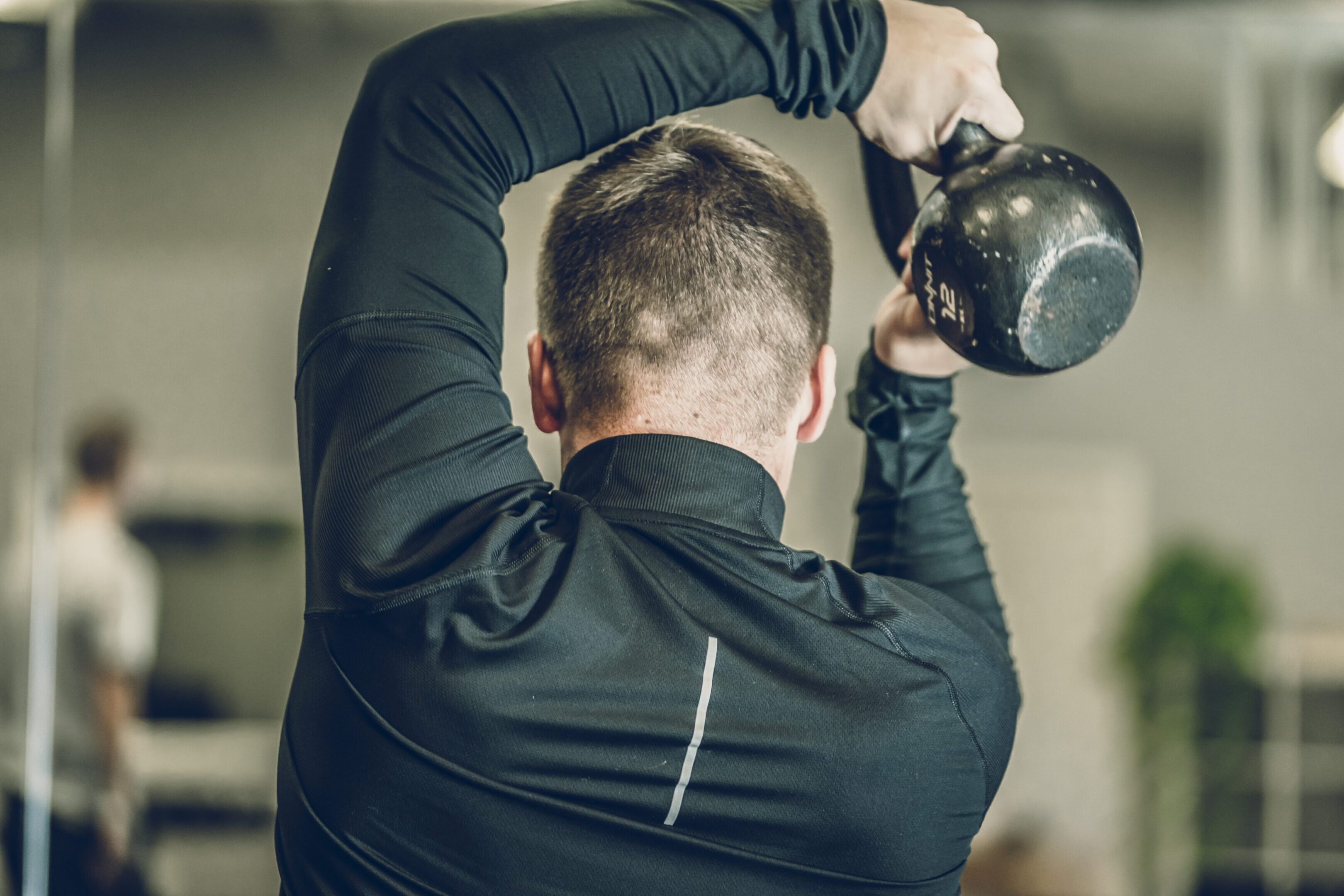 Man performing kettlebell overhead exercise in gym